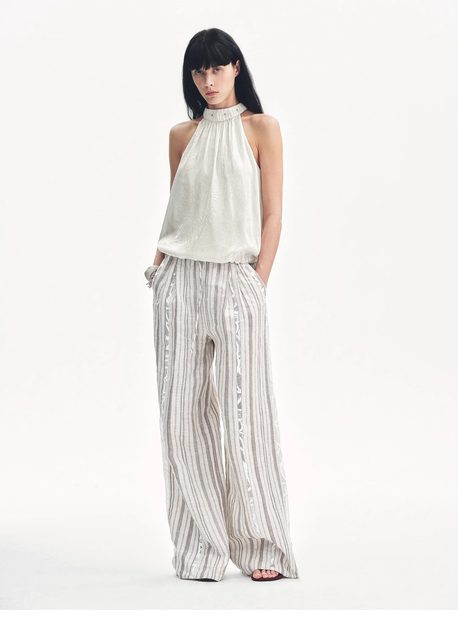 Woman wearing a white halter top and striped pants on a white background