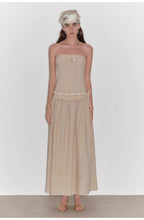 Woman wearing a beige strapless dress with a white background