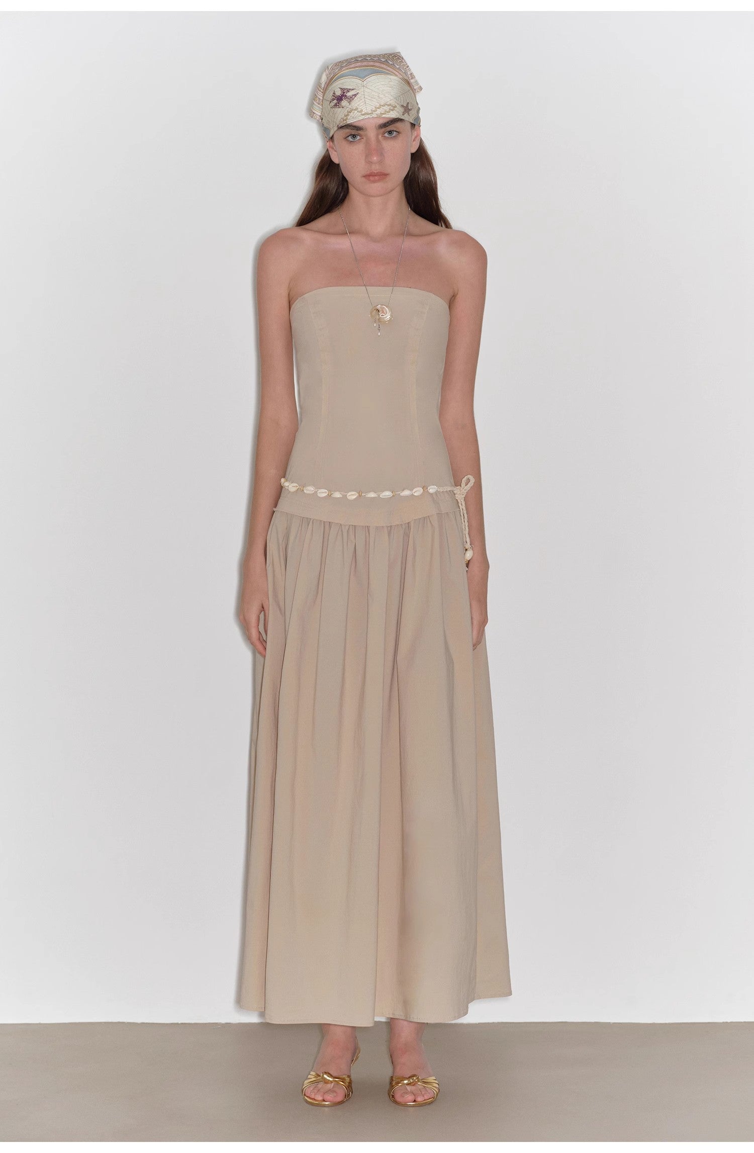 Woman wearing a beige strapless dress with a white background