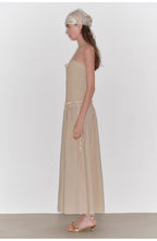 Woman wearing a beige dress with a plain white background