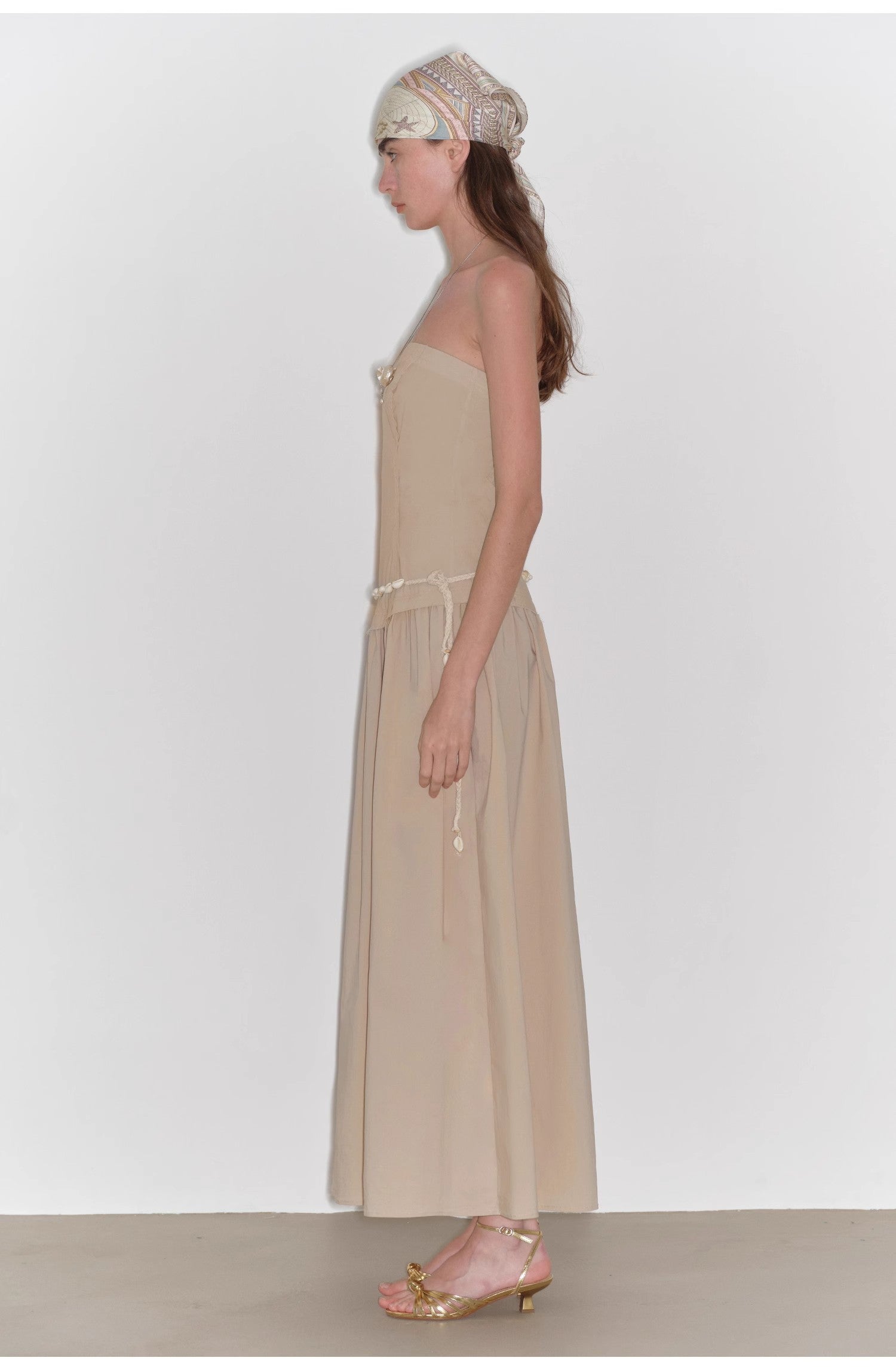 Woman wearing a beige dress with a plain white background
