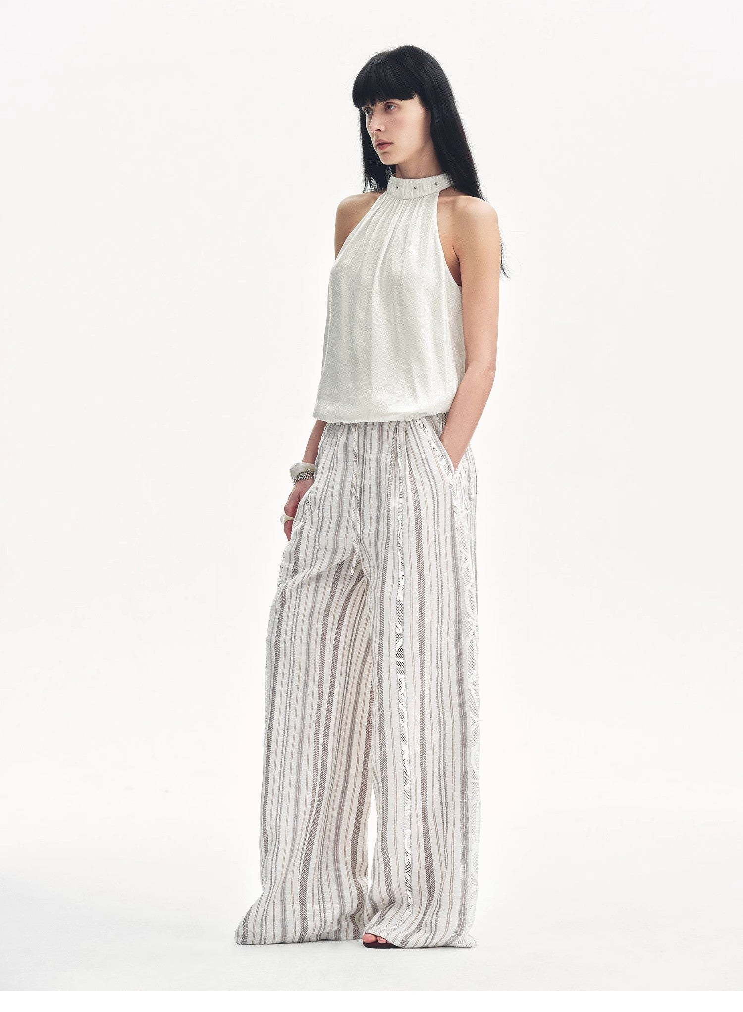 Woman wearing a white halter top and striped pants on a white background