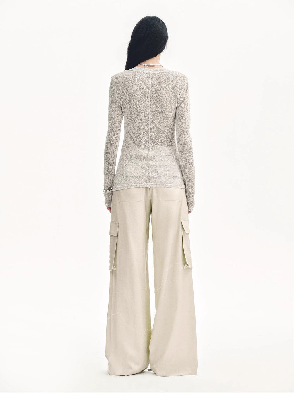 Person wearing a textured long-sleeve top and wide-leg pants on a white background