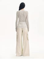 Person wearing a textured long-sleeve top and wide-leg pants on a white background