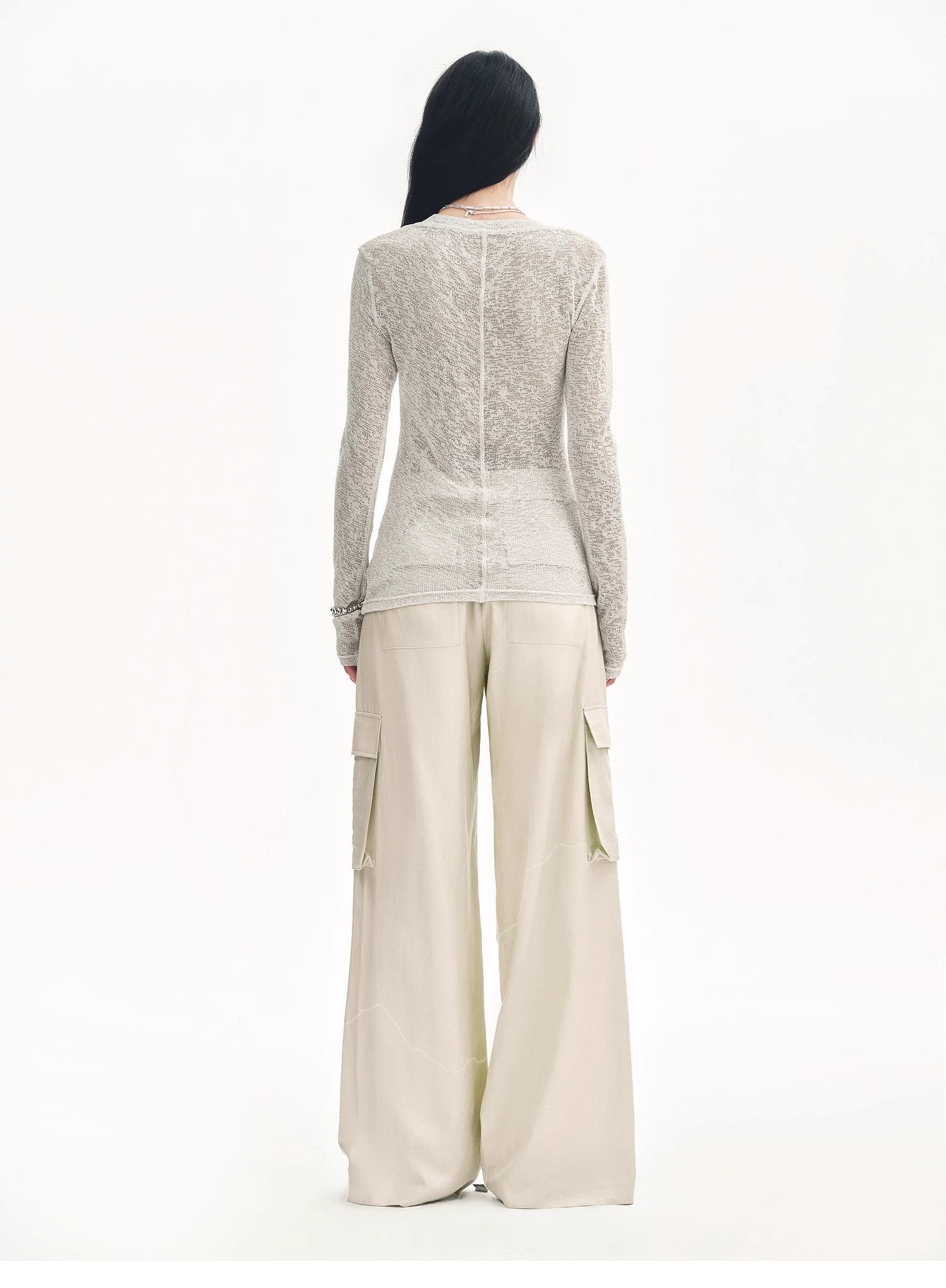Person wearing a textured long-sleeve top and wide-leg pants on a white background