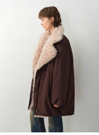 Person wearing a brown coat with beige fur collar against a white background