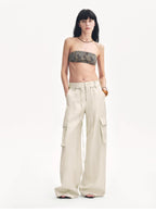 Woman wearing a strapless top and beige cargo pants on a white background