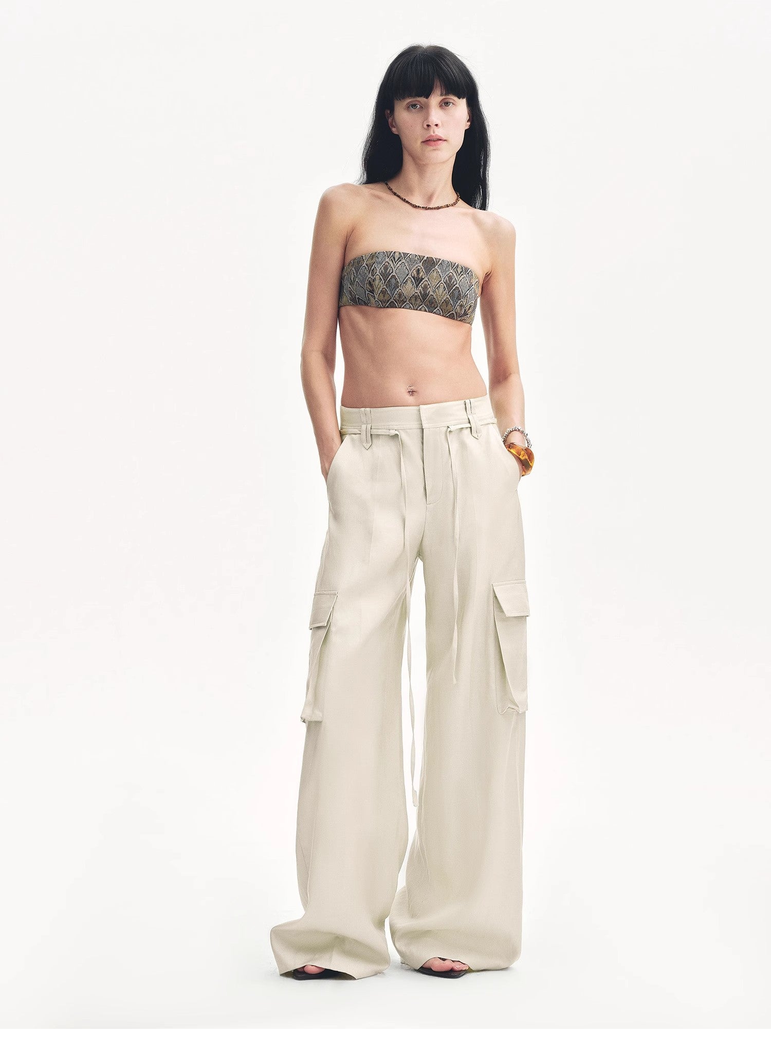 Woman wearing a strapless top and beige cargo pants on a white background