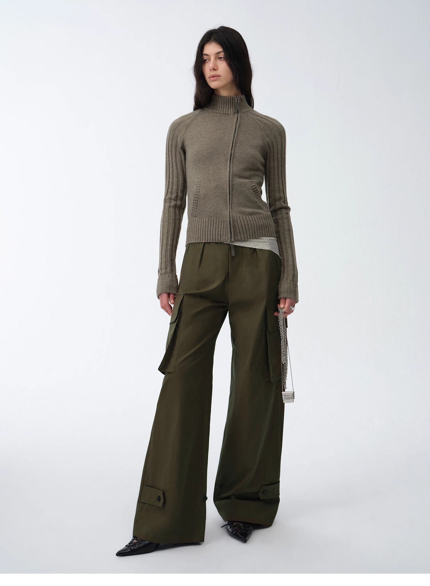 Person wearing a green knit cardigan and wide-leg pants on a white background