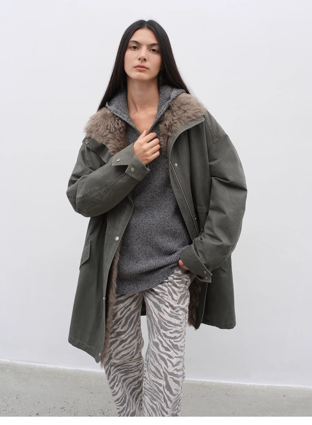 Woman wearing a gray coat with fur hood against a white background