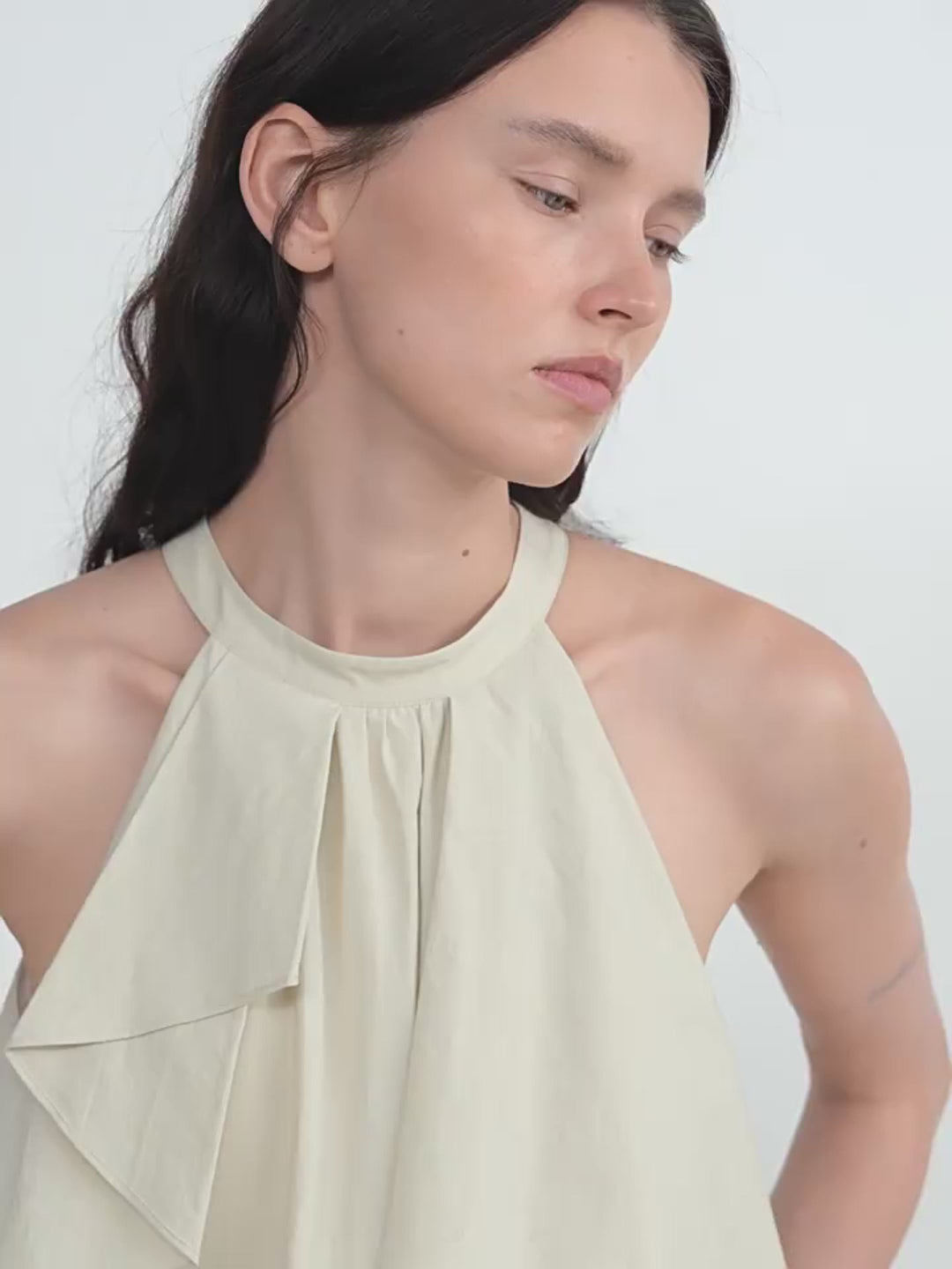 Woman wearing a light green halter top against a white background