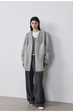 Person wearing a gray cardigan over a gray outfit against a white background