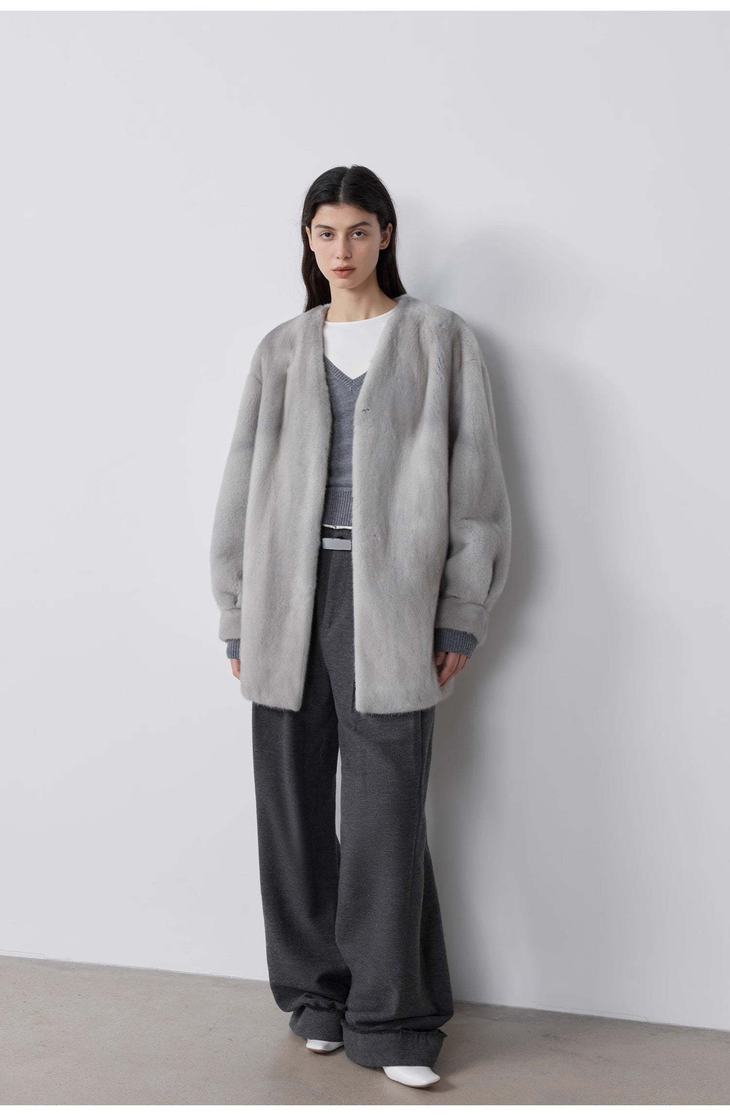 Person wearing a gray cardigan over a gray outfit against a white background