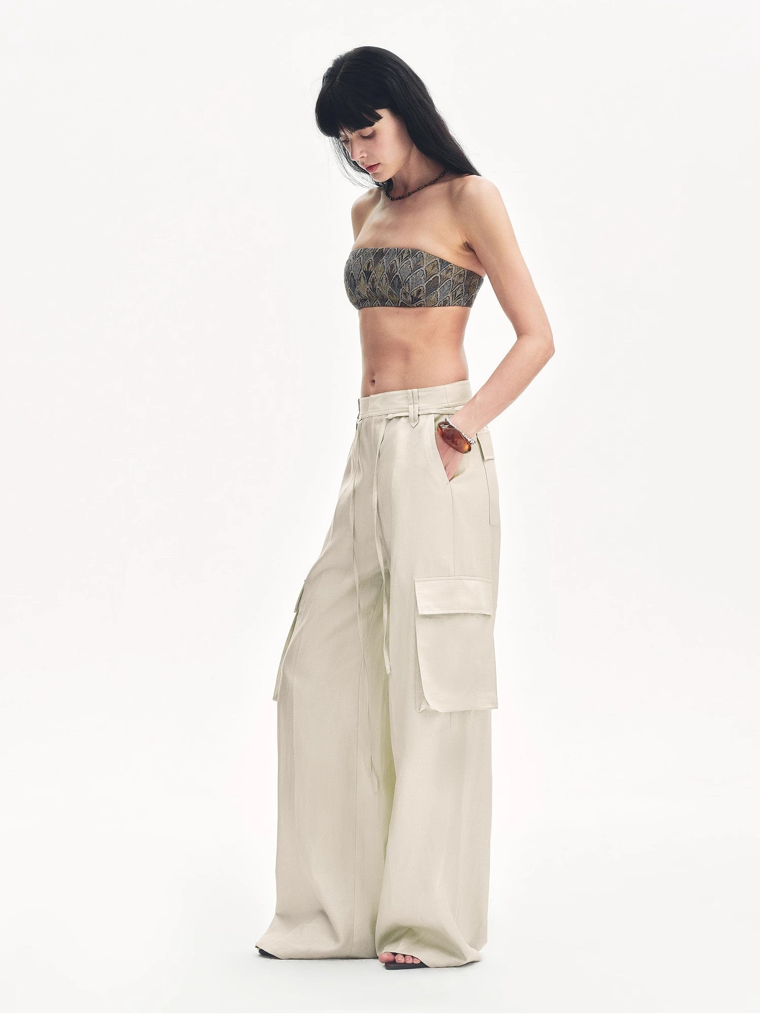 Woman wearing a strapless top and beige cargo pants on a white background