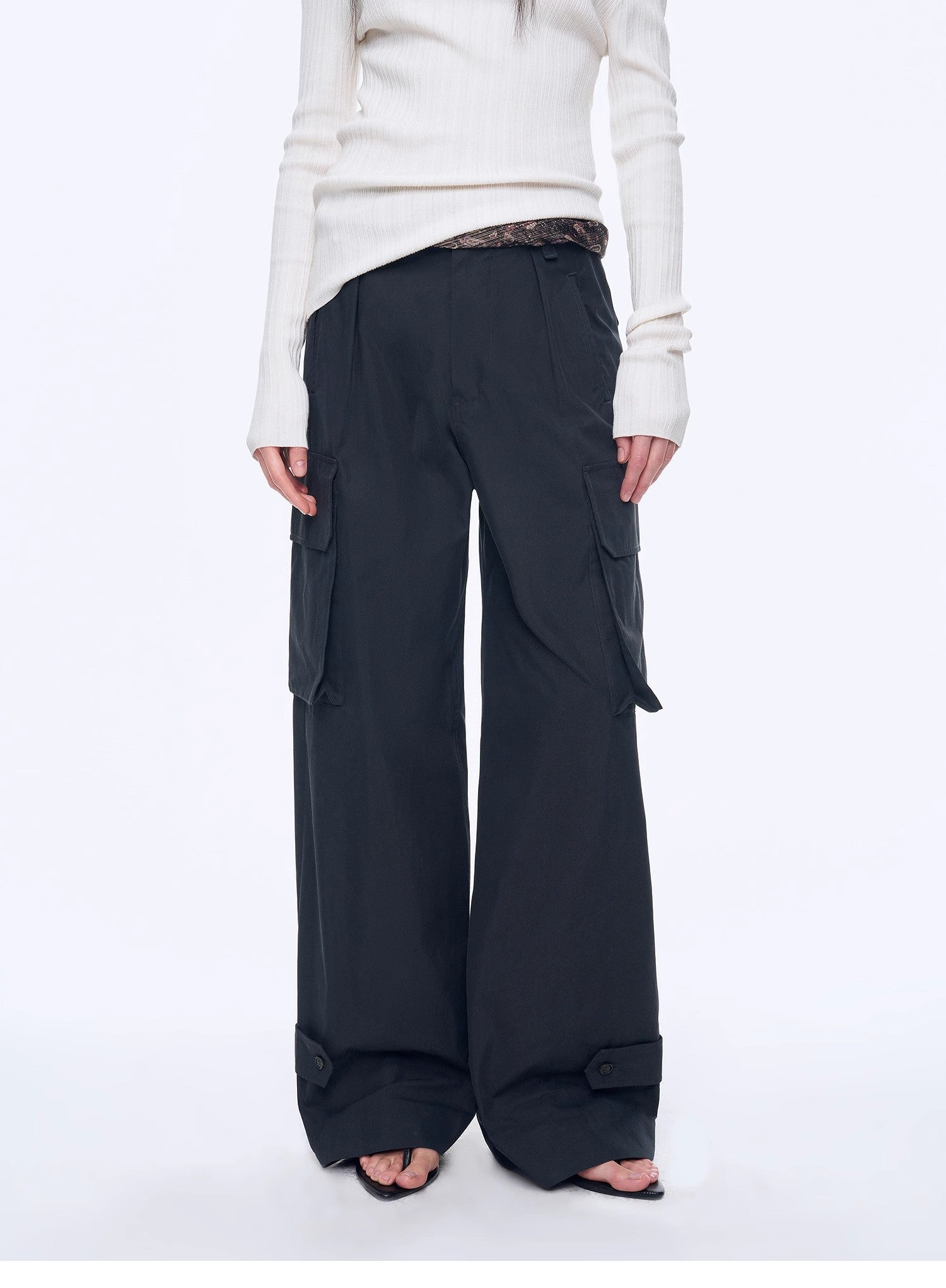 Person wearing black cargo pants and a white top on a white background