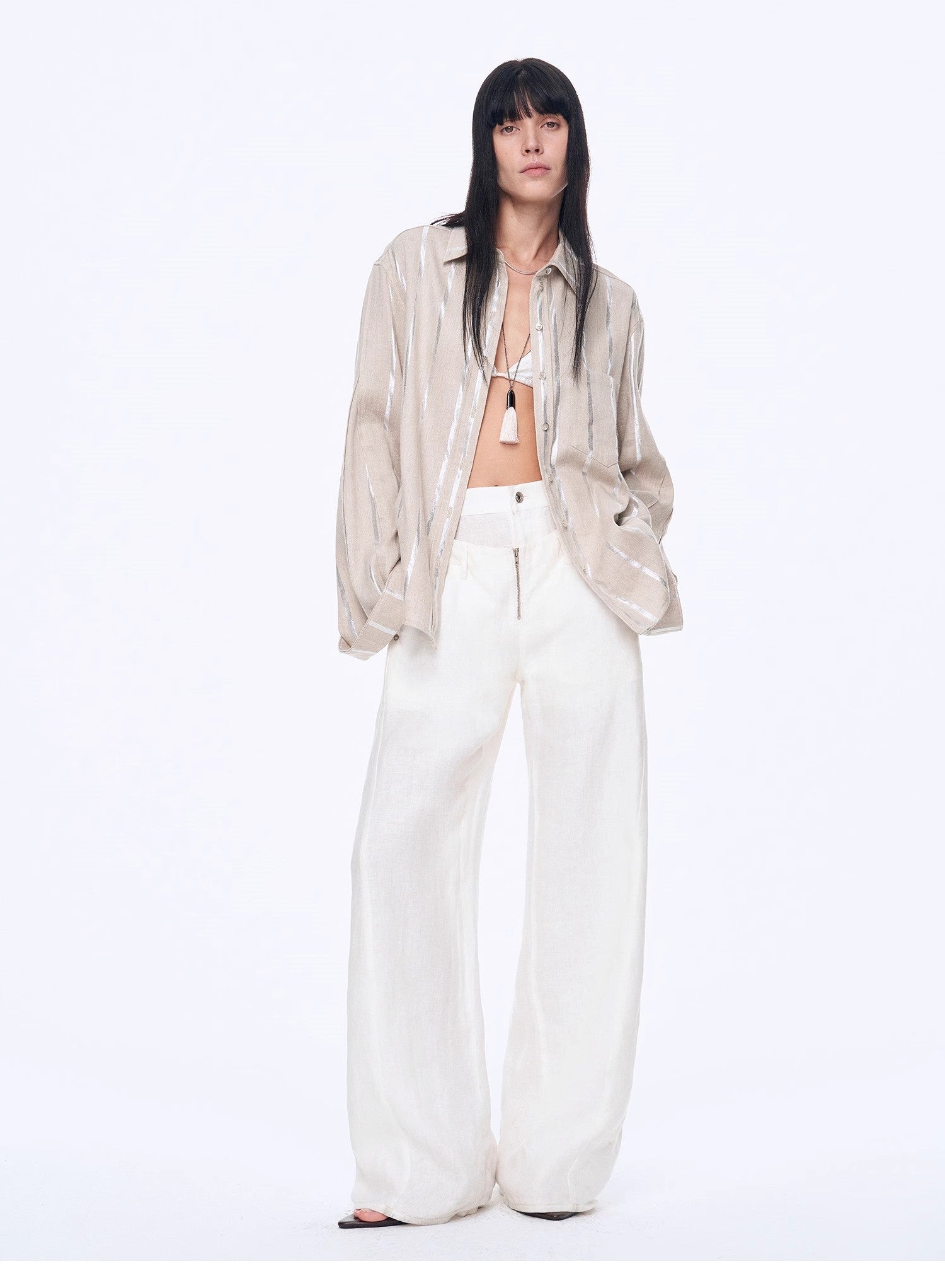Woman wearing a beige blouse and white pants on a white background