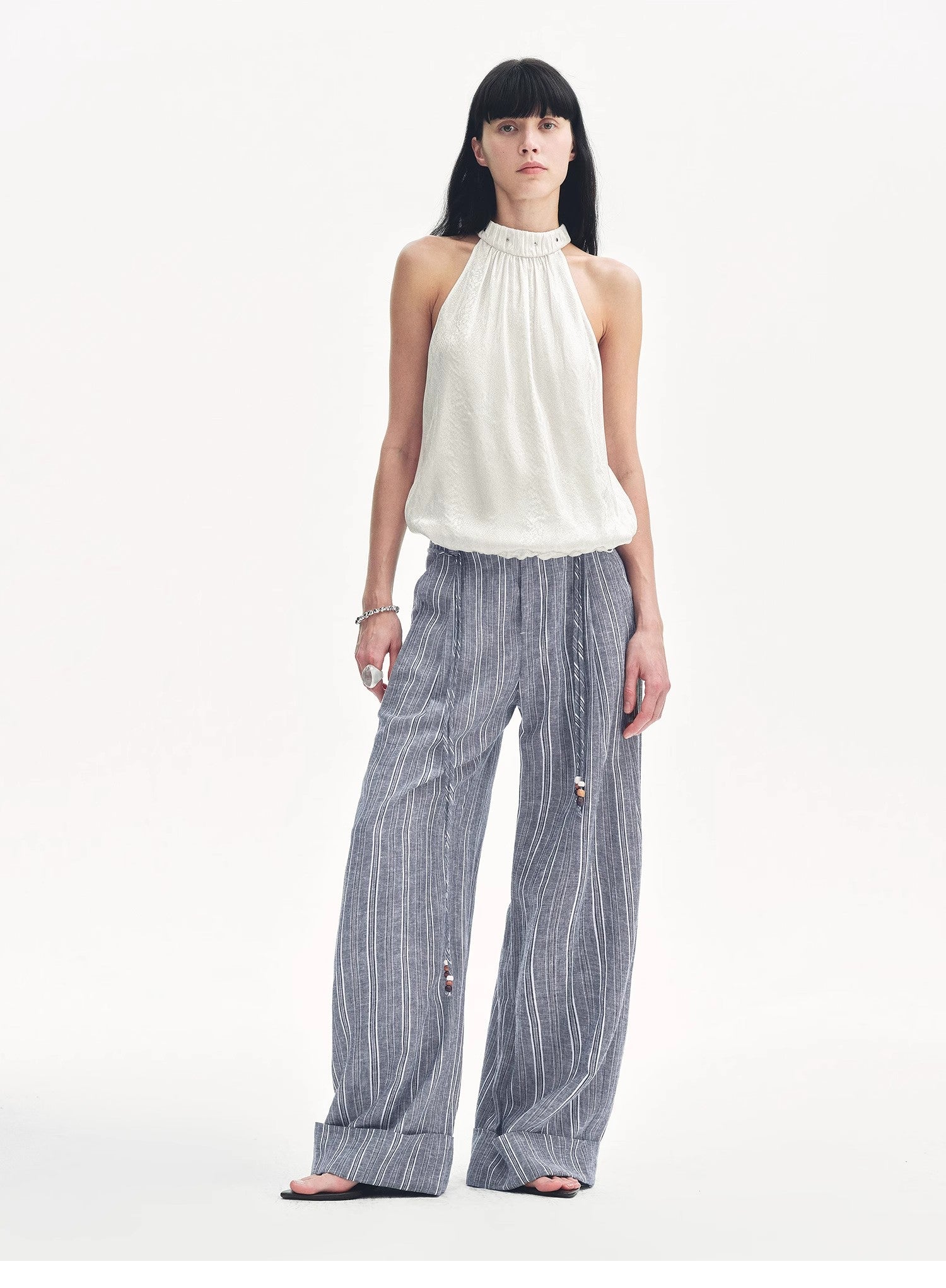 Woman wearing a white top and blue striped pants on a white background