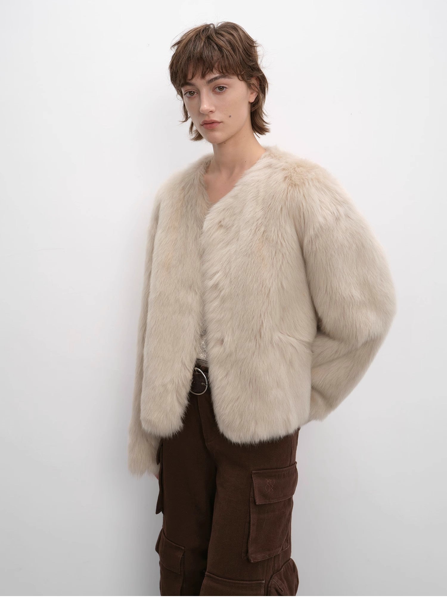 Person wearing a beige fur coat against a white background