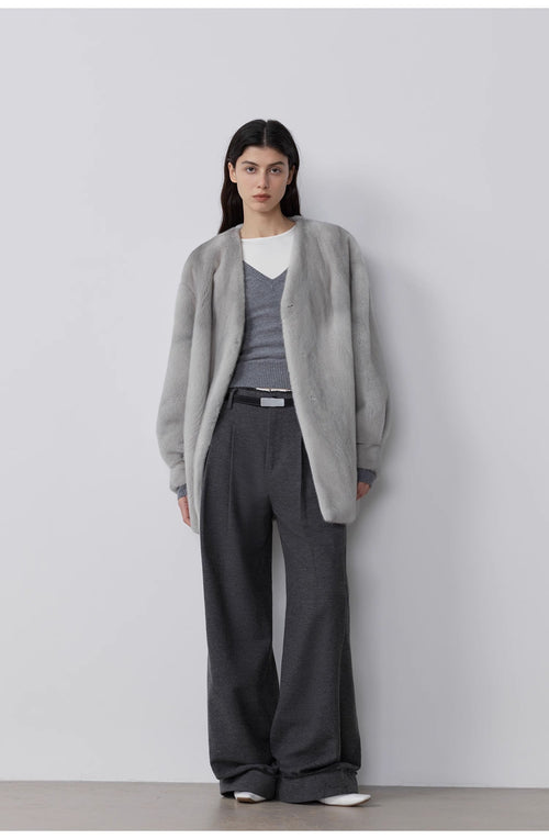 Person wearing a gray cardigan, gray sweater, and gray pants against a white background