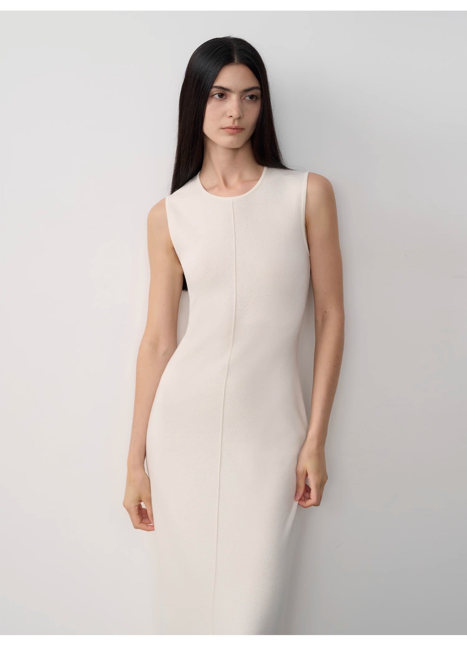 Woman wearing a white sleeveless dress against a plain background