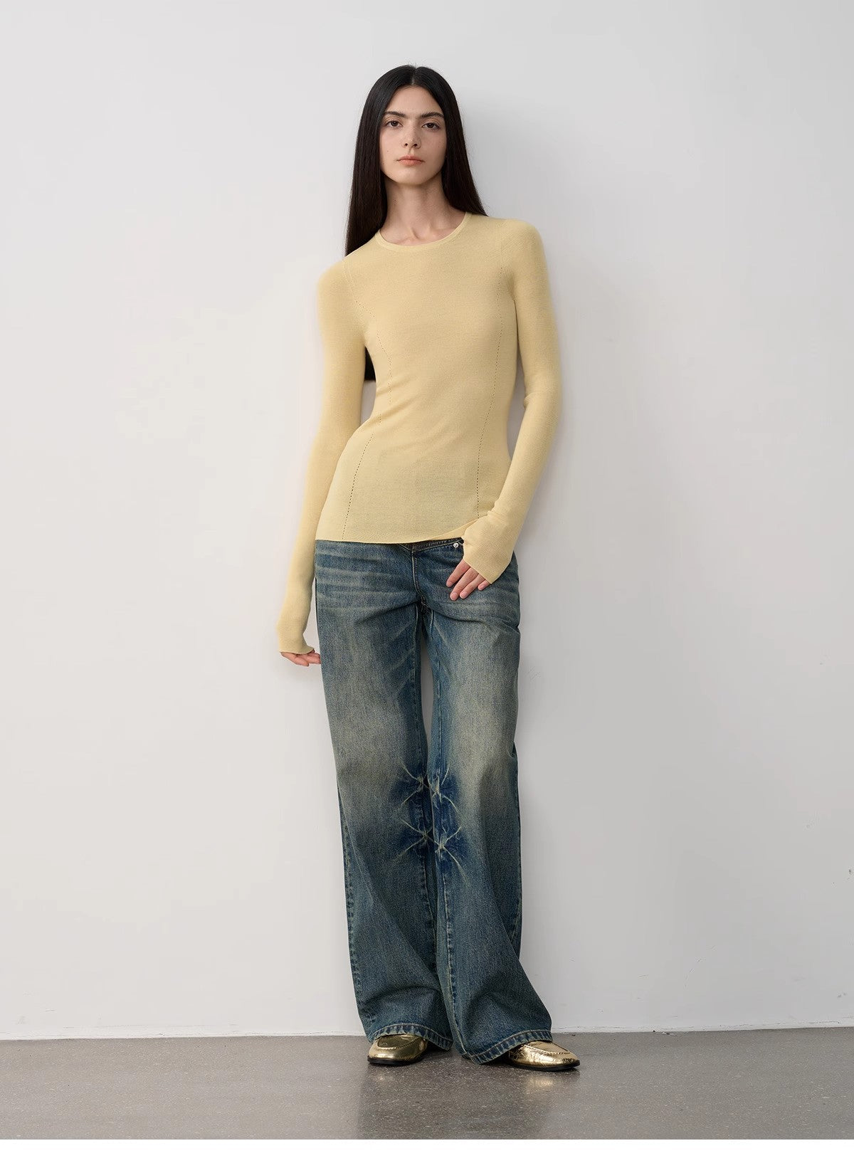 Woman wearing a yellow top and blue jeans against a white background