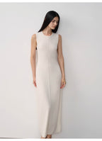 Woman wearing a white sleeveless dress against a plain background