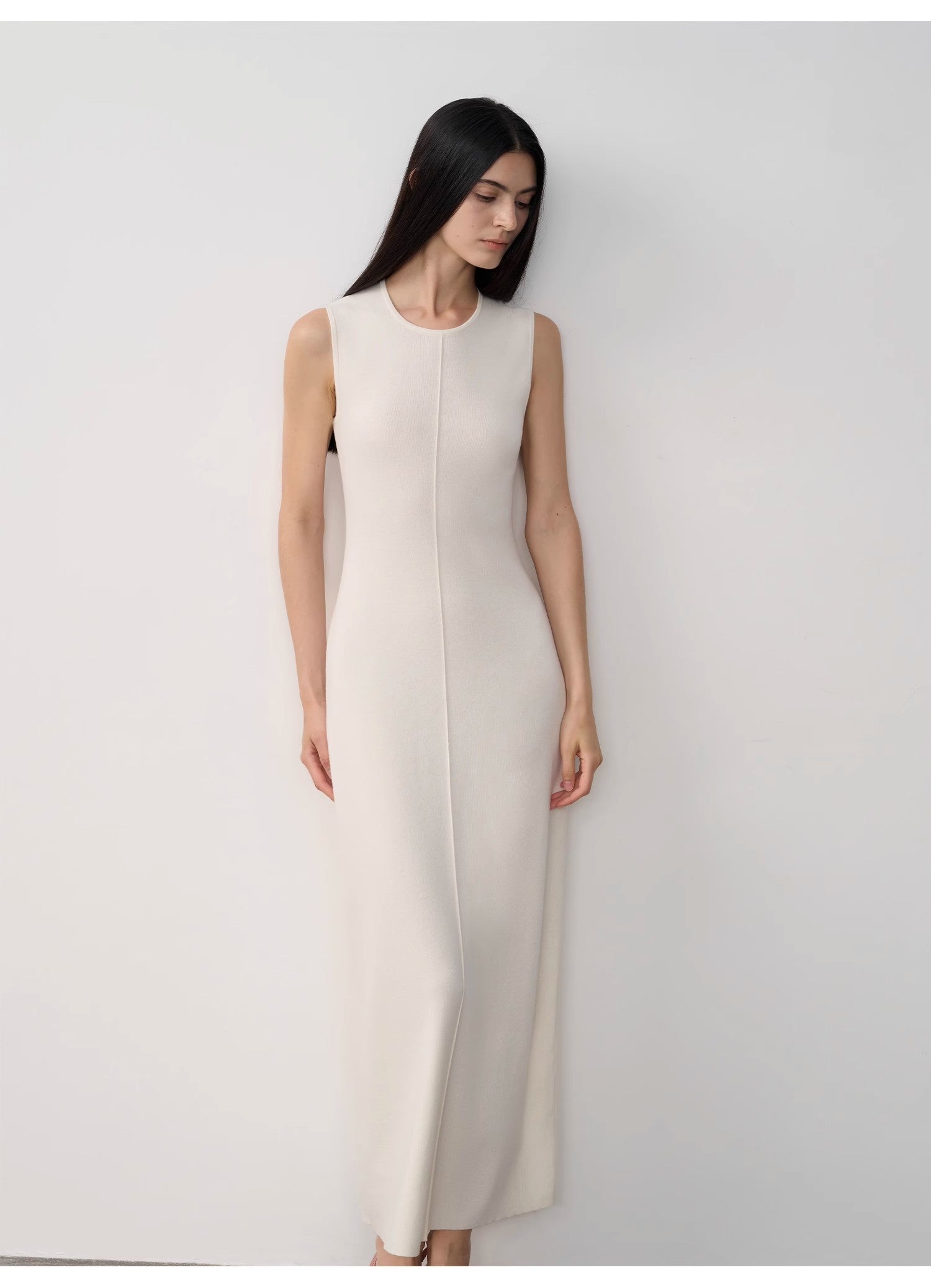 Woman wearing a white sleeveless dress against a plain background