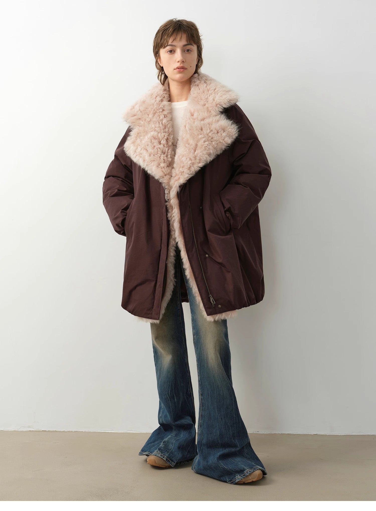 Person wearing a brown coat with beige fur collar against a white background