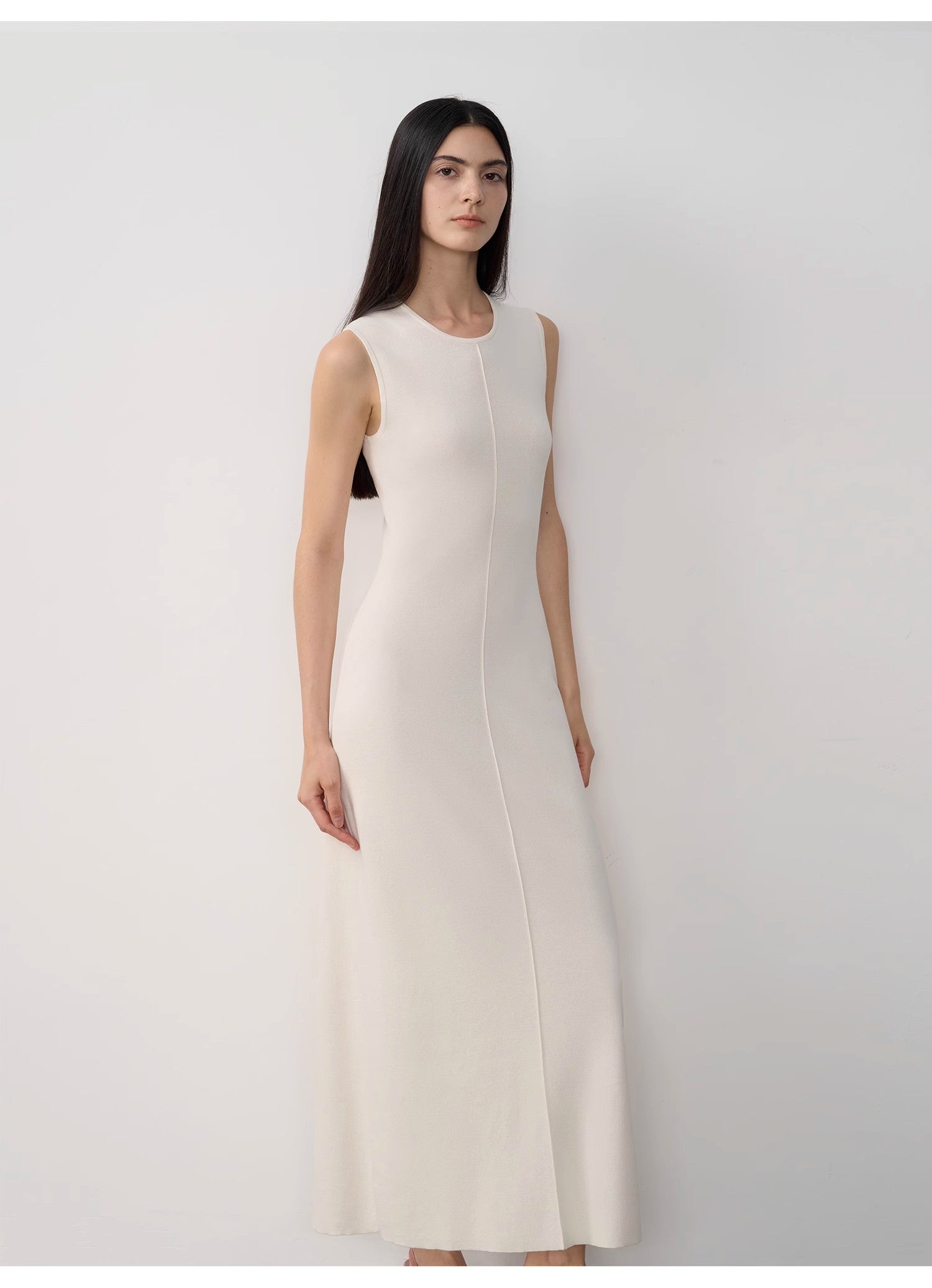 Woman wearing a white sleeveless dress against a plain background