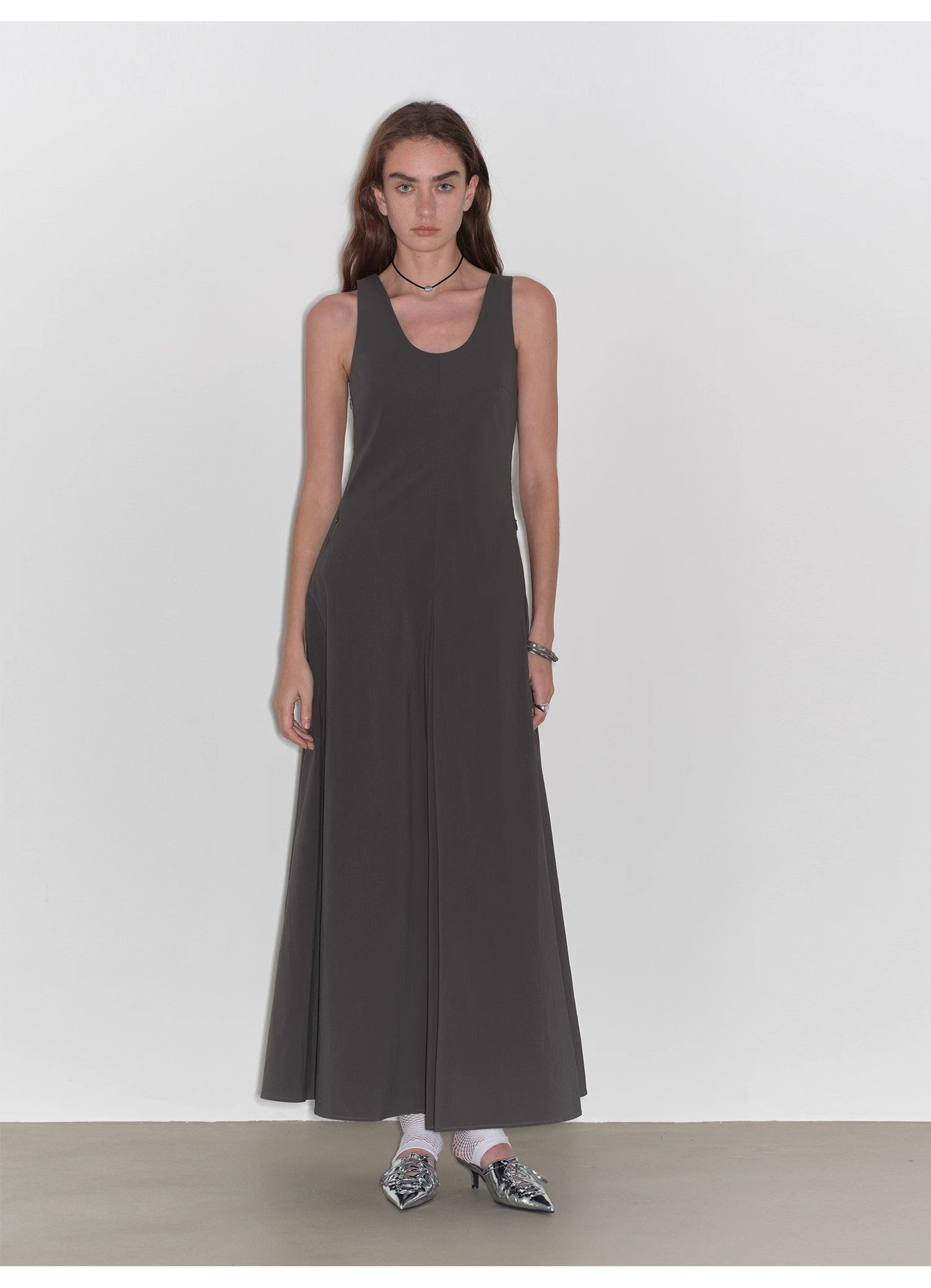 Woman wearing a long dark gray dress against a white background