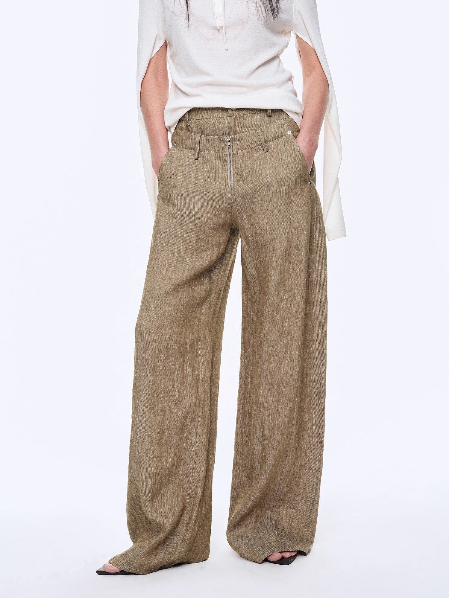 Person wearing beige wide-leg pants on a white background
