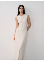 Woman wearing a white sleeveless dress against a plain background