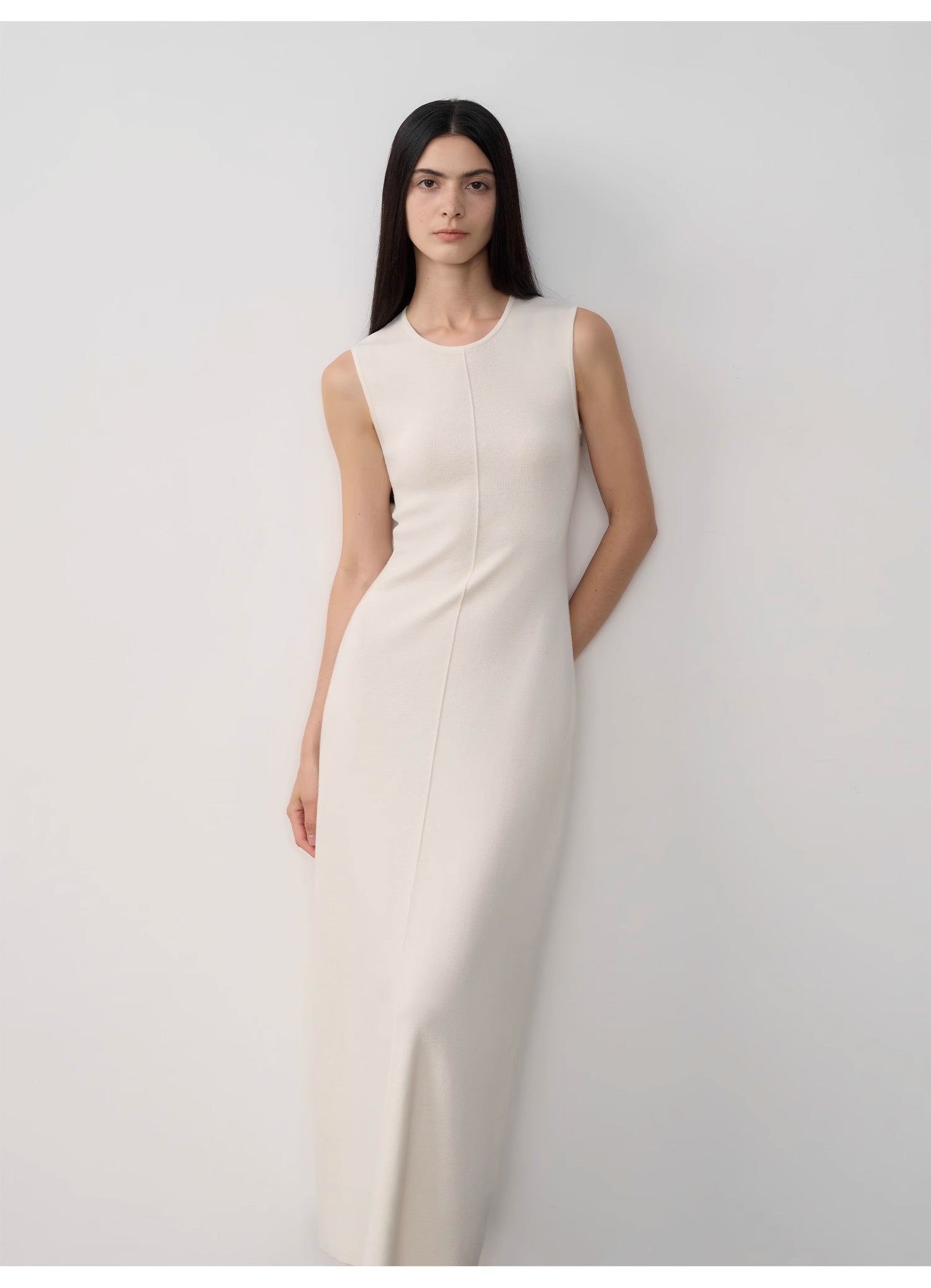 Woman wearing a white sleeveless dress against a plain background