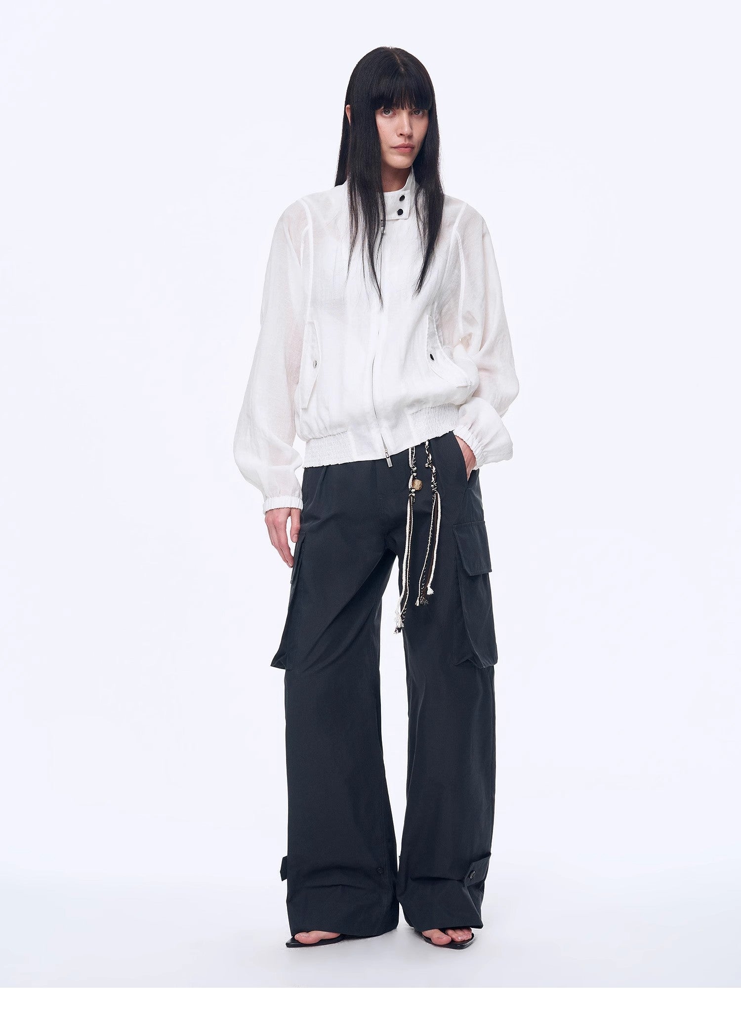 Person wearing a white jacket and black pants on a white background
