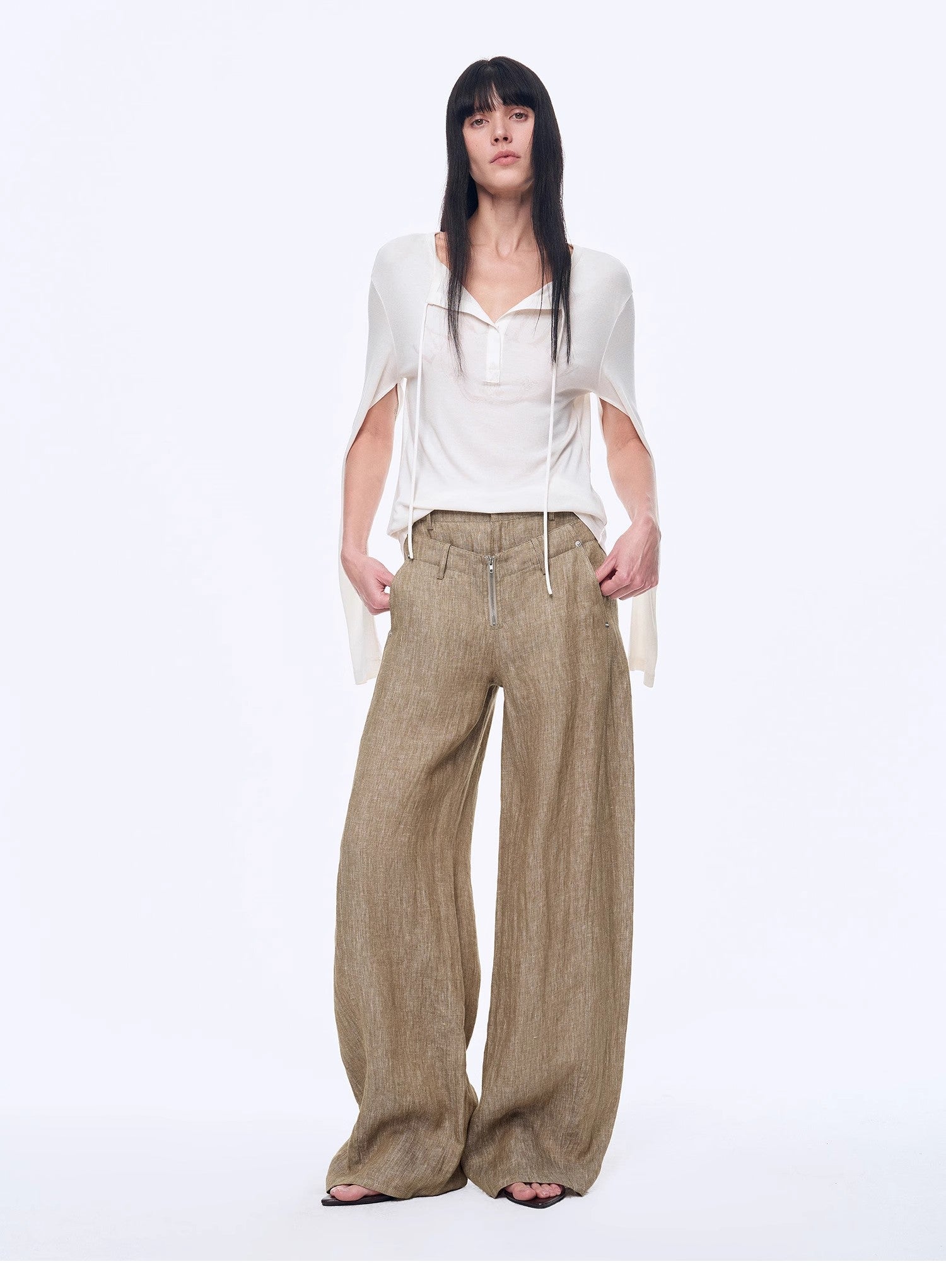 Woman wearing a white top and beige wide-leg pants on a white background