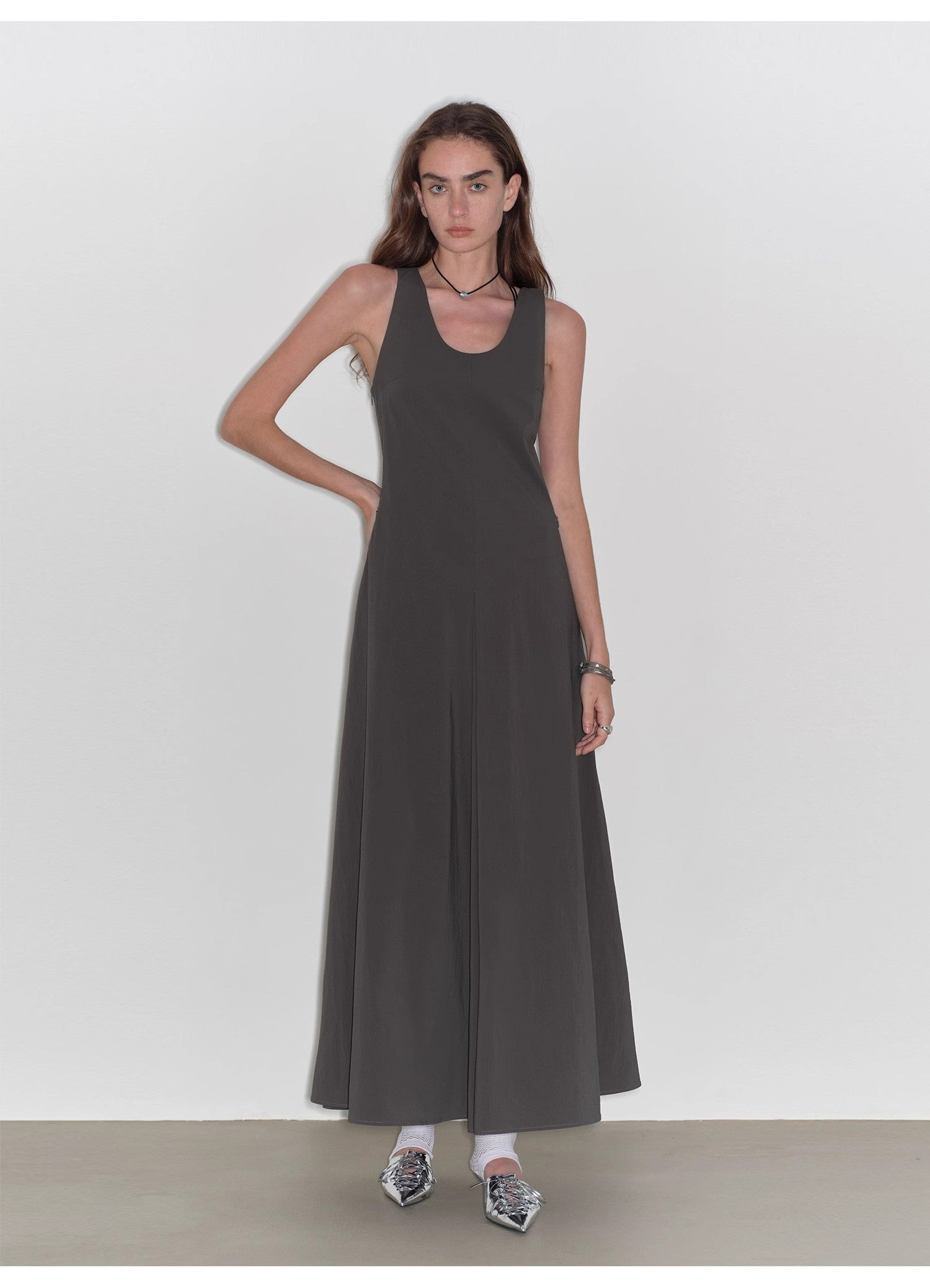 Woman wearing a long dark gray dress against a white background