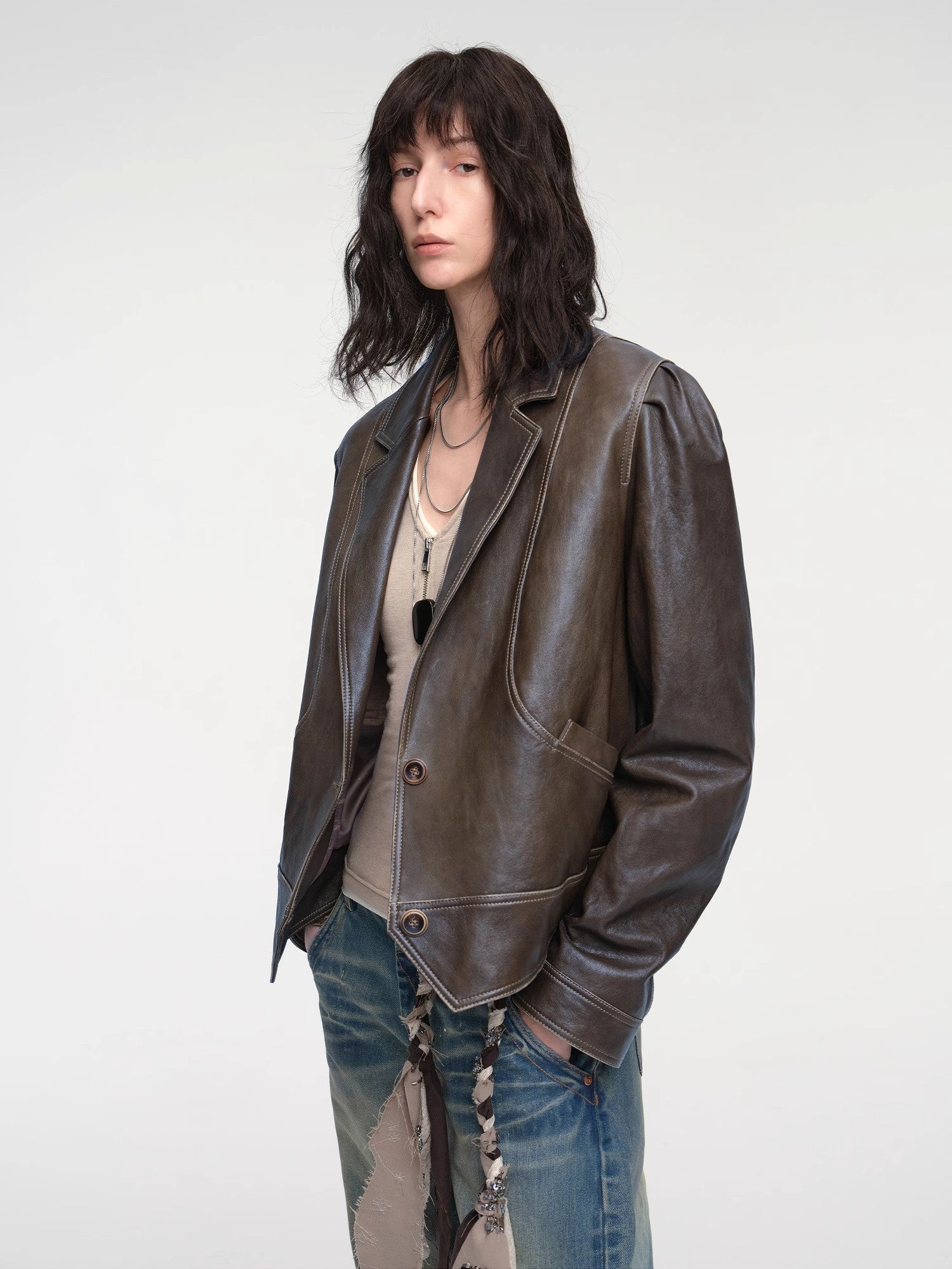 Person wearing a brown leather jacket and jeans on a white background