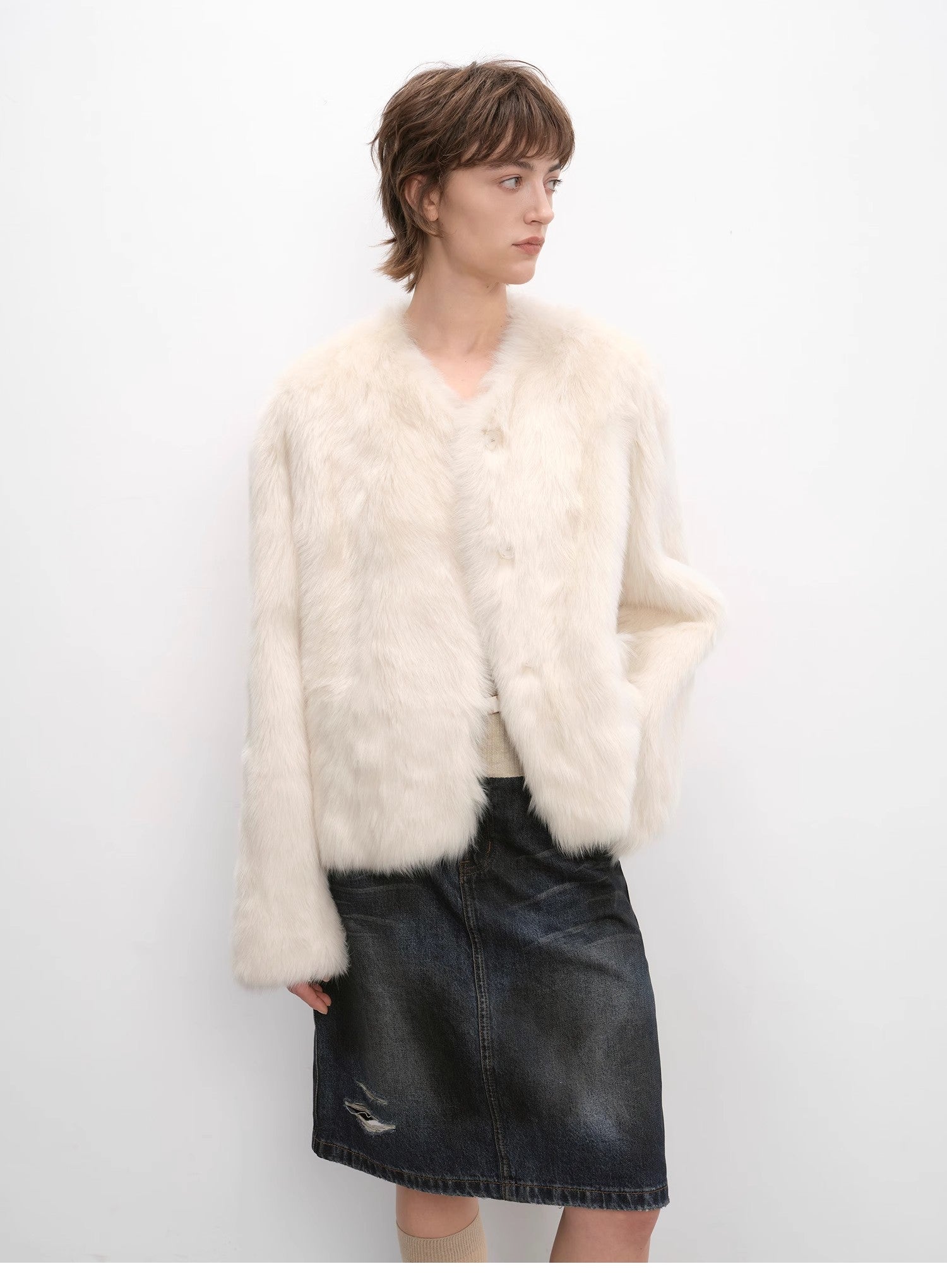Woman wearing a white fur coat and black skirt against a white background