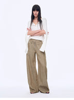 Woman wearing a white blouse and beige wide-leg pants on a white background