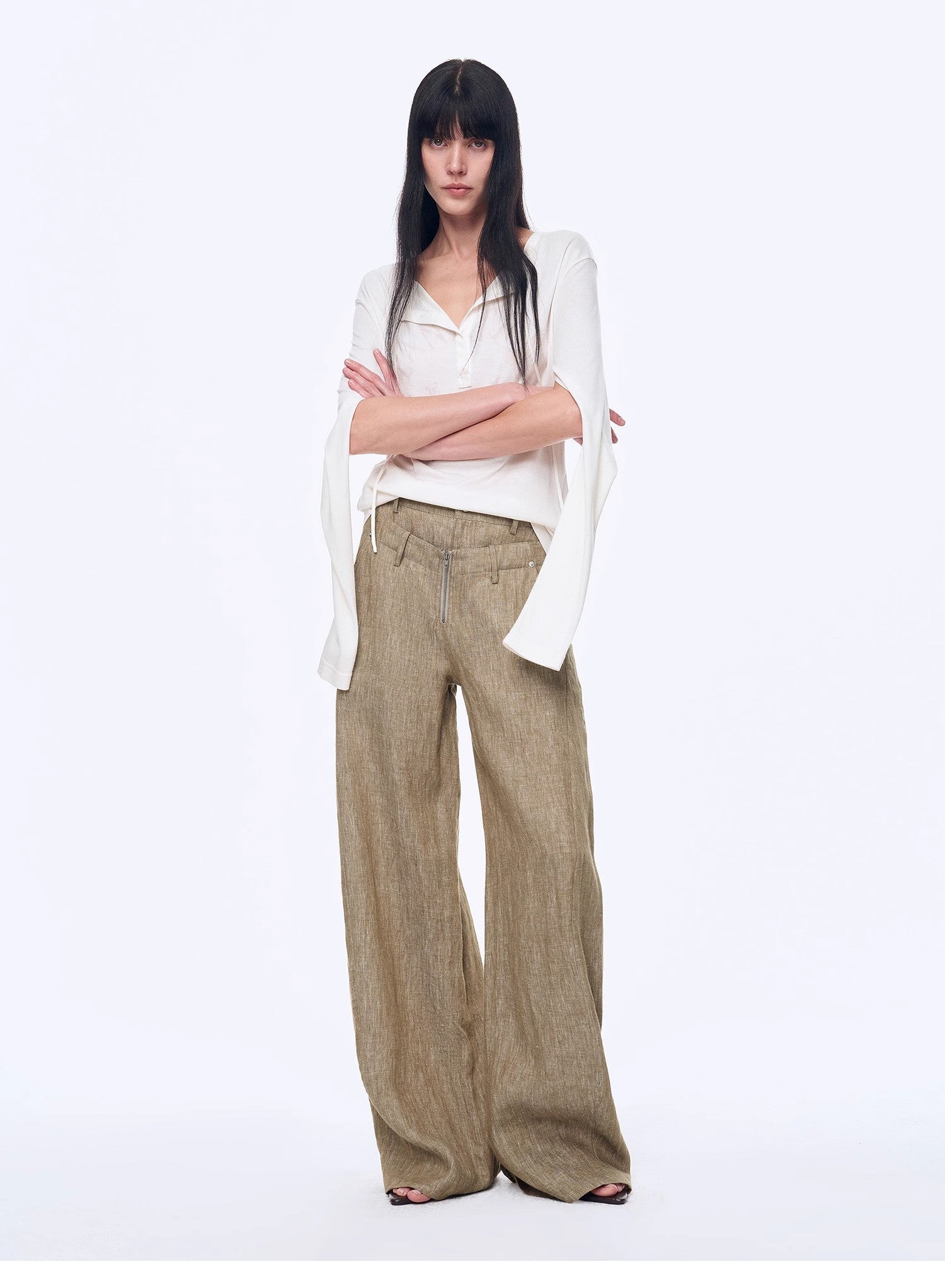 Woman wearing a white blouse and beige wide-leg pants on a white background
