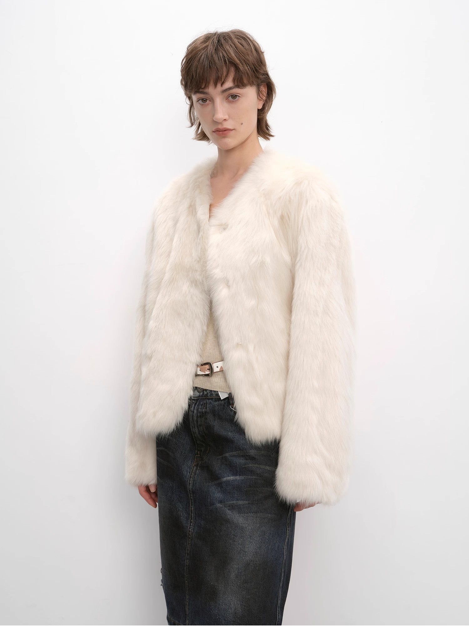 Person wearing a white fur coat against a plain background