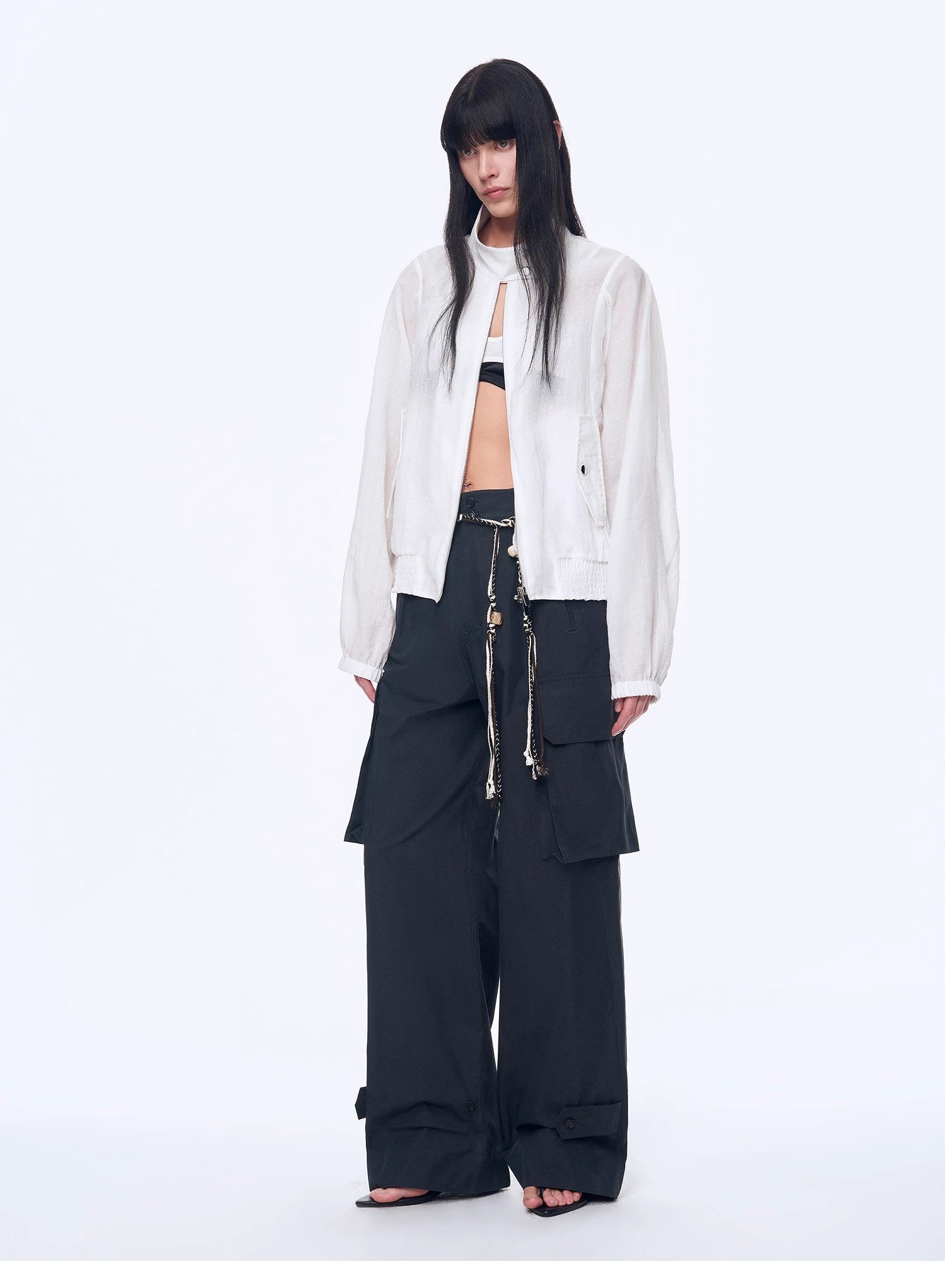 Person wearing a white shirt and black pants with zippers on a white background