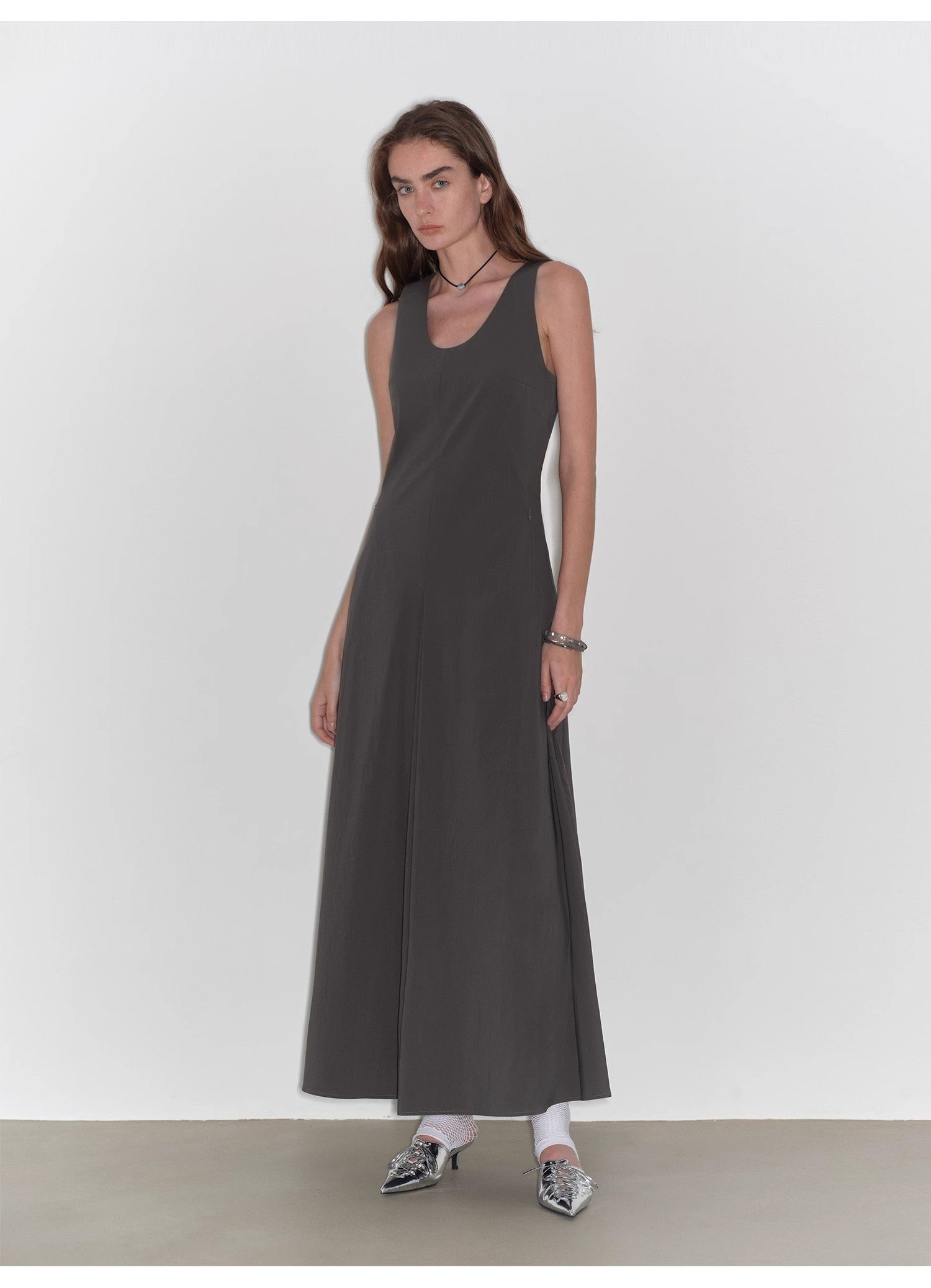 Woman wearing a long dark gray dress against a white background