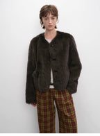 Person wearing a dark brown fur coat and plaid pants against a white background