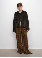 Person wearing a dark fur coat and plaid pants against a white background