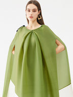Woman wearing a green cape on a white background