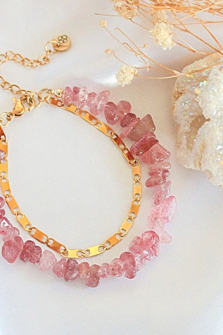 Two pink beaded bracelets on a white surface with decorative elements.
