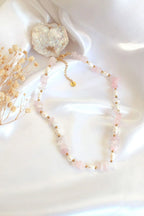 Necklace with pink beads and gold accents on a white fabric background