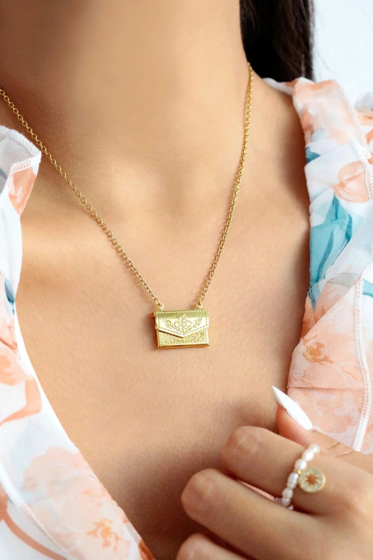 Gold necklace with a pendant worn by a person, with a blurred background.
