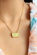 Gold necklace with a pendant on a person wearing a floral dress.